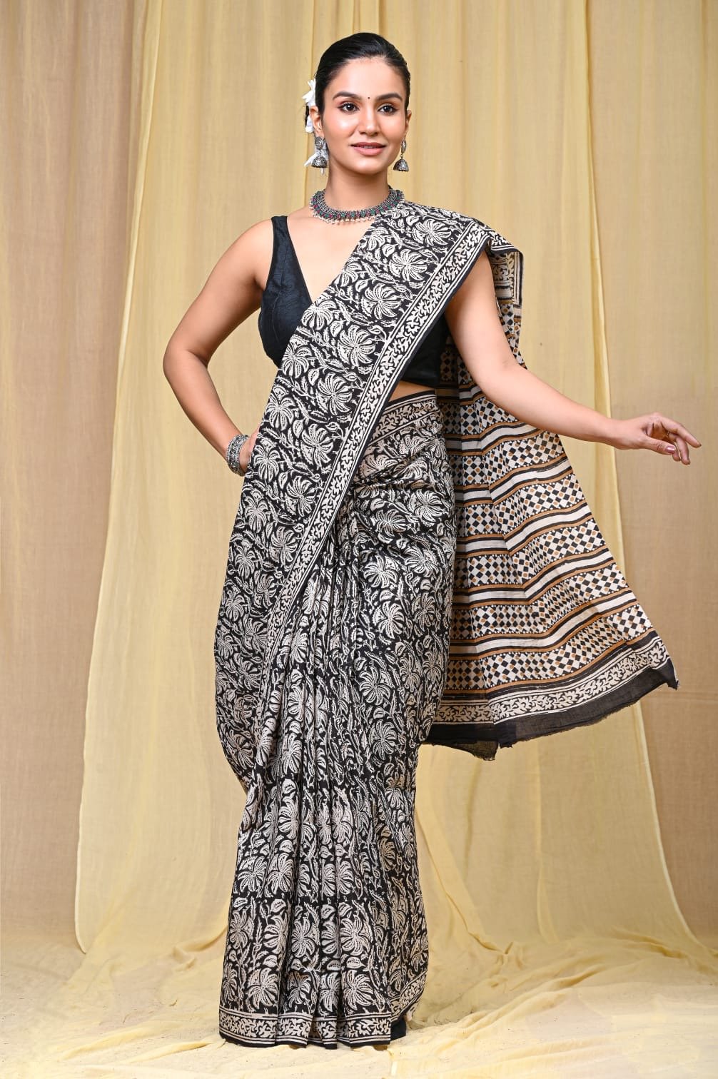 Black saree with white floral motifs, striped and dotted pallu