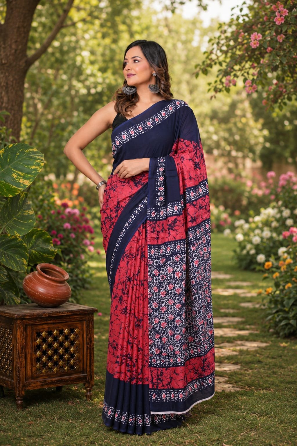 Navy blue and red saree with floral and geometric motifs in a garden setting