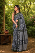 Navy saree with floral motifs and geometric border in a natural setting
