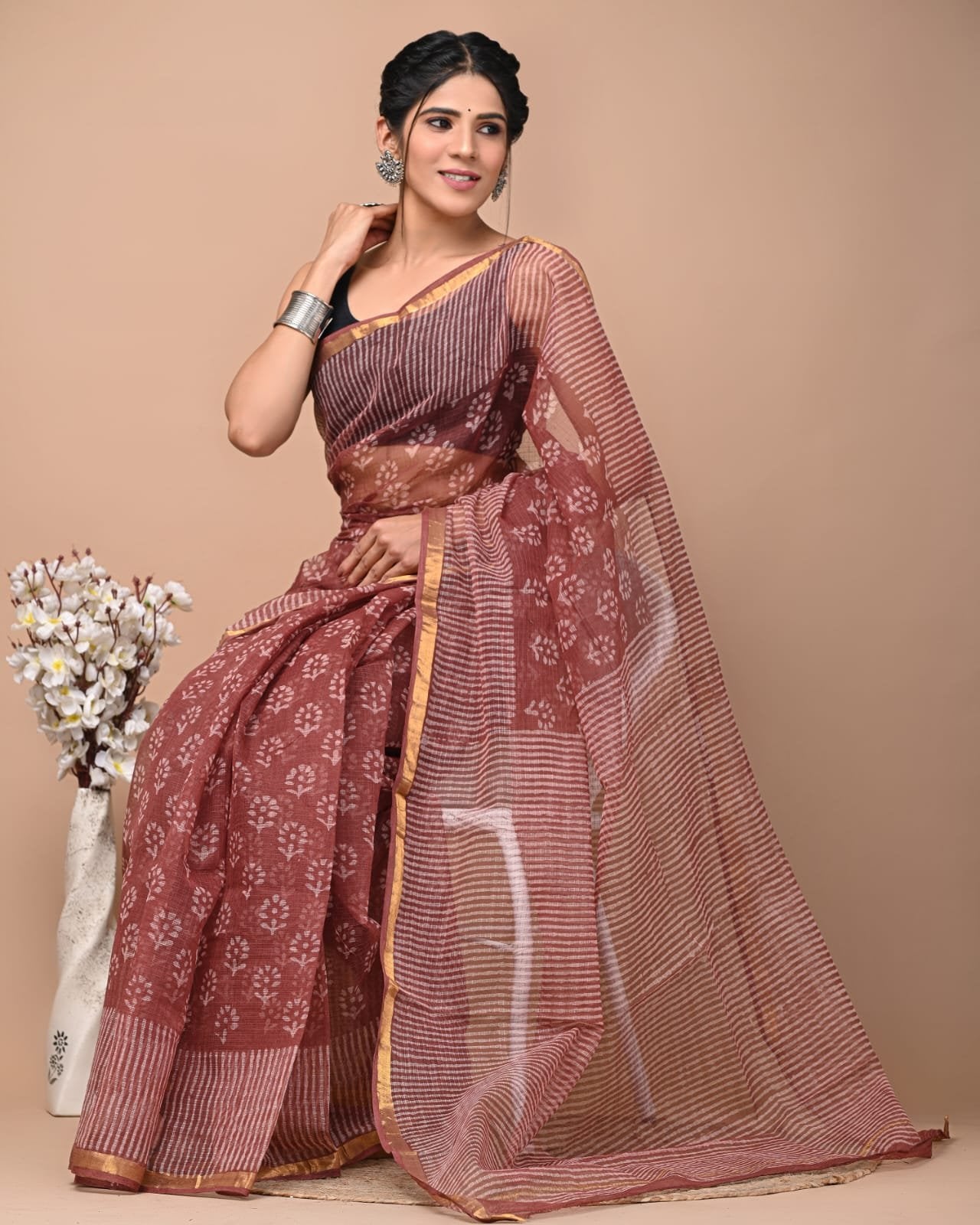 A maroon saree with white floral motifs and gold border, lightweight Kota Doriya fabric