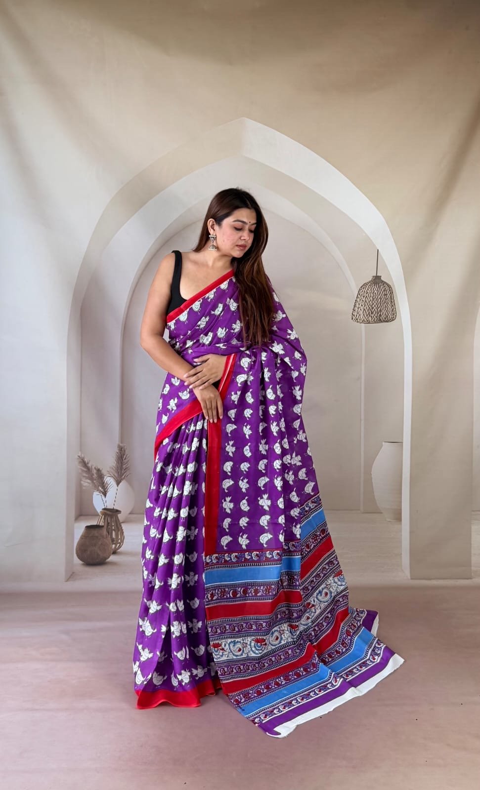 Purple saree with floral motifs, red border, and intricate pallu design in red and blue